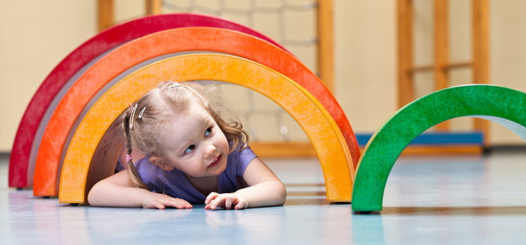 alle kouluikäinen lapsi ryömii värikkäässä jumppatunnelista
